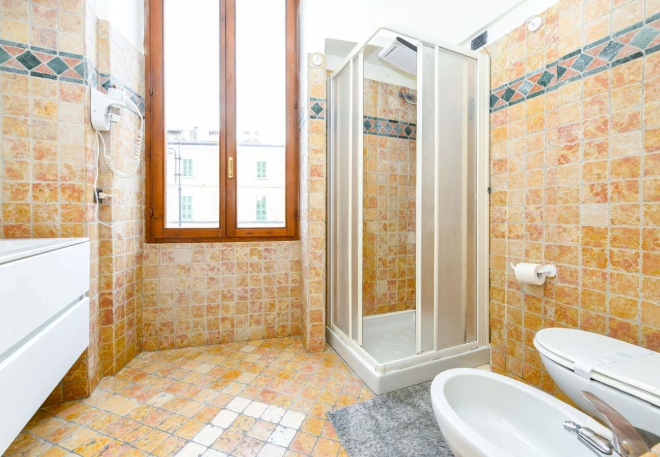 Nowoczesna łazienka z kamienną okładziną, prysznicem, bidetem i oknem w Desenzano