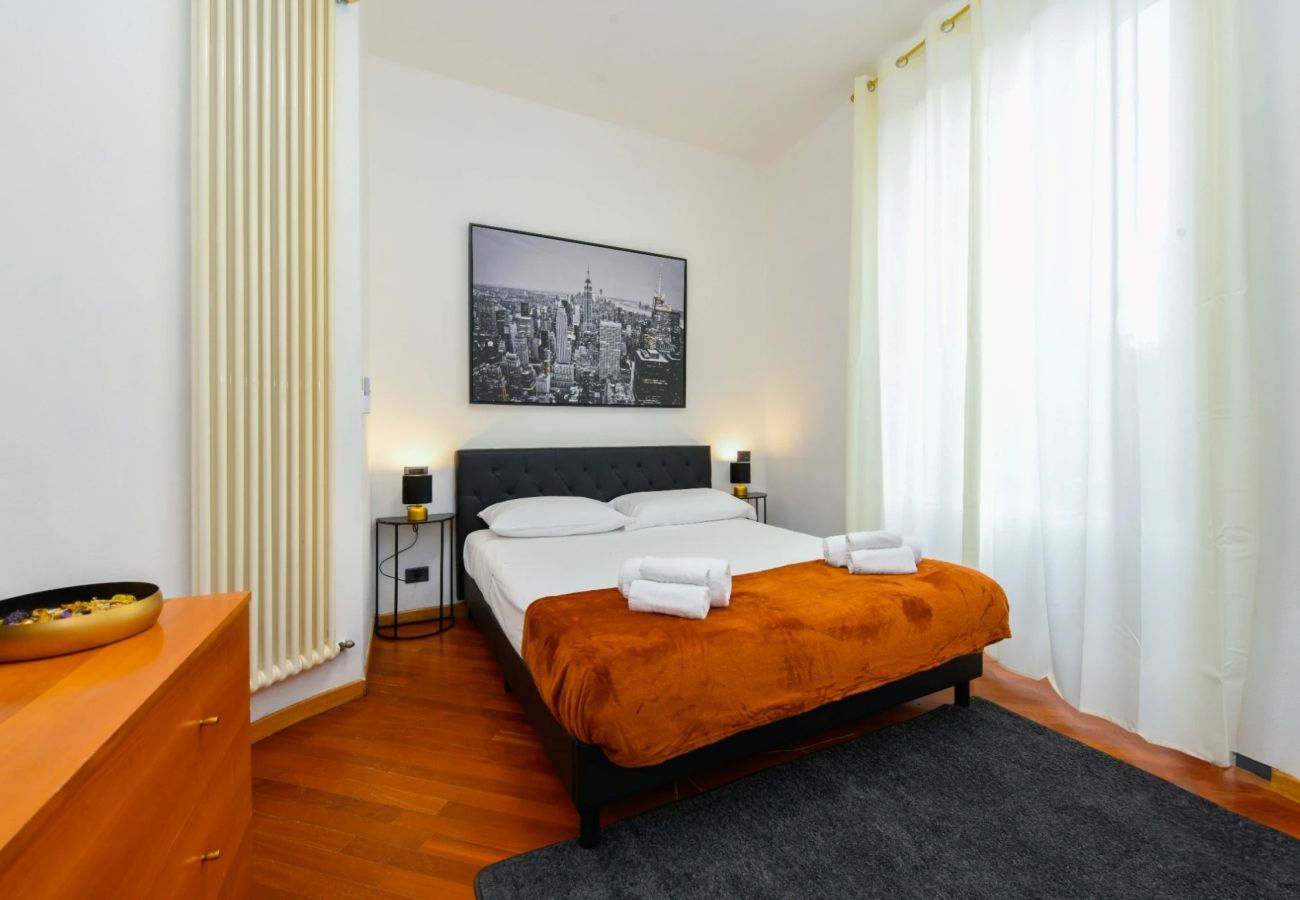 Nowoczesna sypialnia dwuosobowa z pomarańczowymi detalami i obrazem w Desenzano