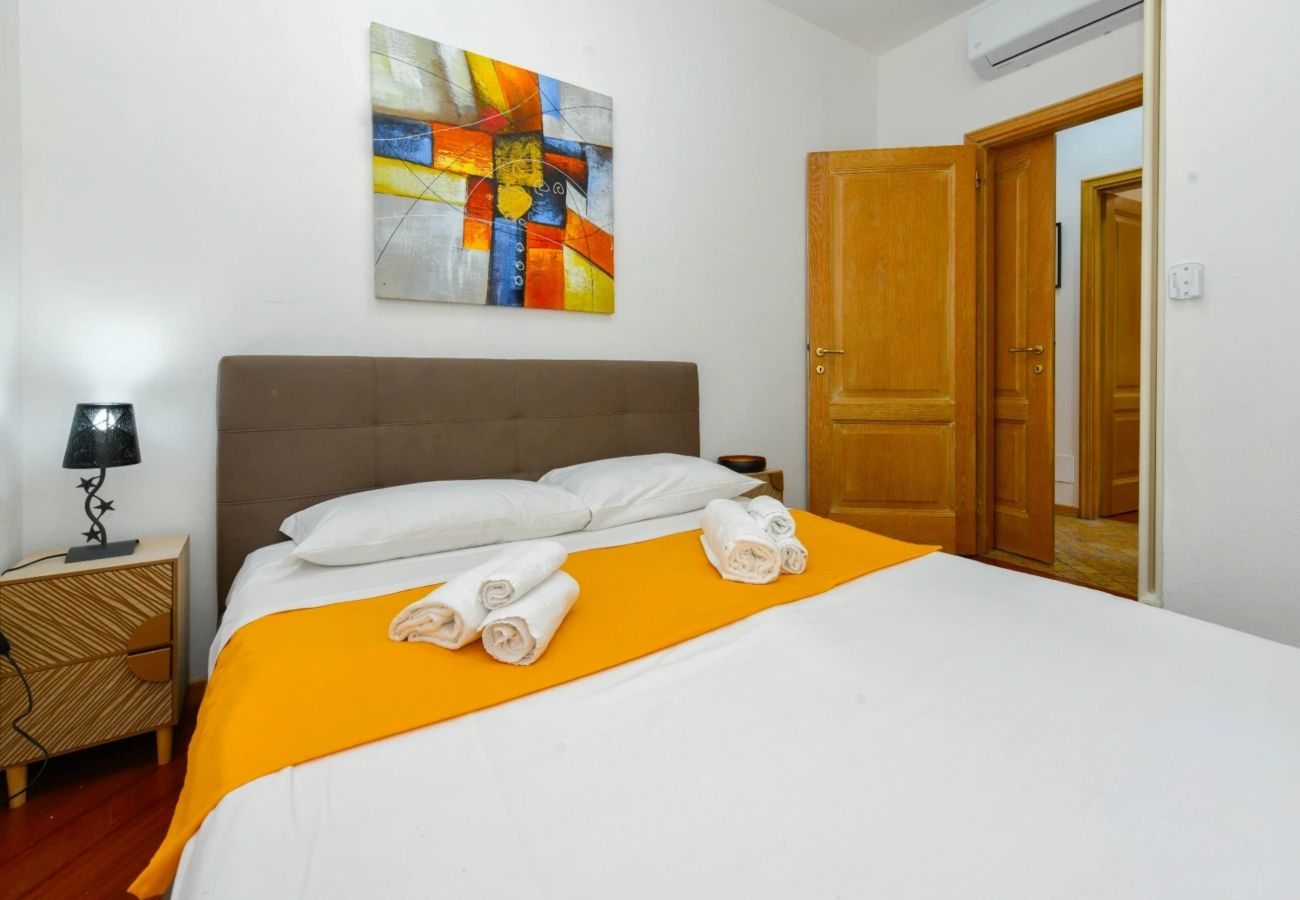 Sypialnia z brązowym zagłówkiem, pomarańczową narzutą i obrazem abstrakcyjnym w Desenzano