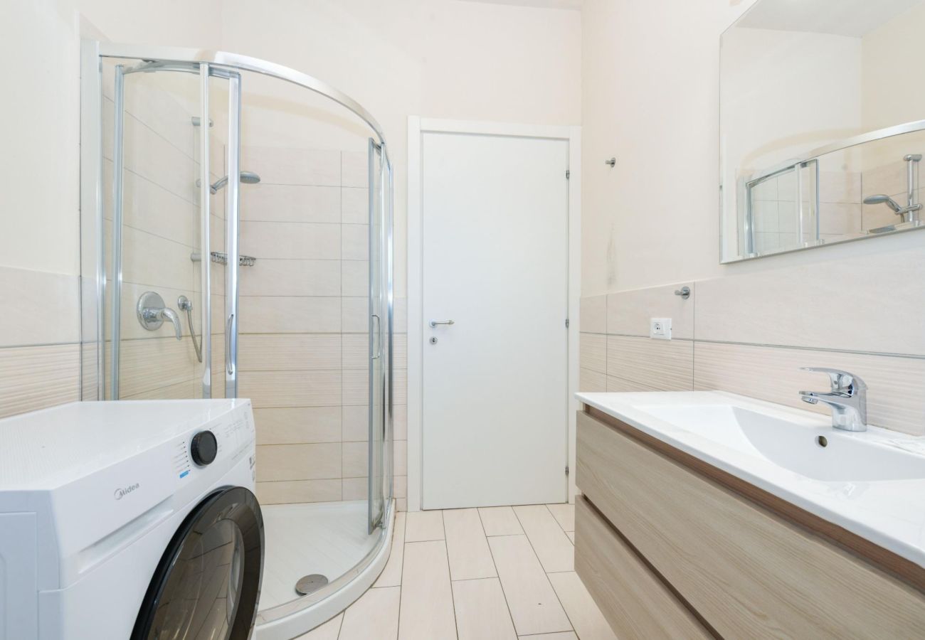 Łazienka z kabiną prysznicową,pralką i drewnianą szafką w Desenzano