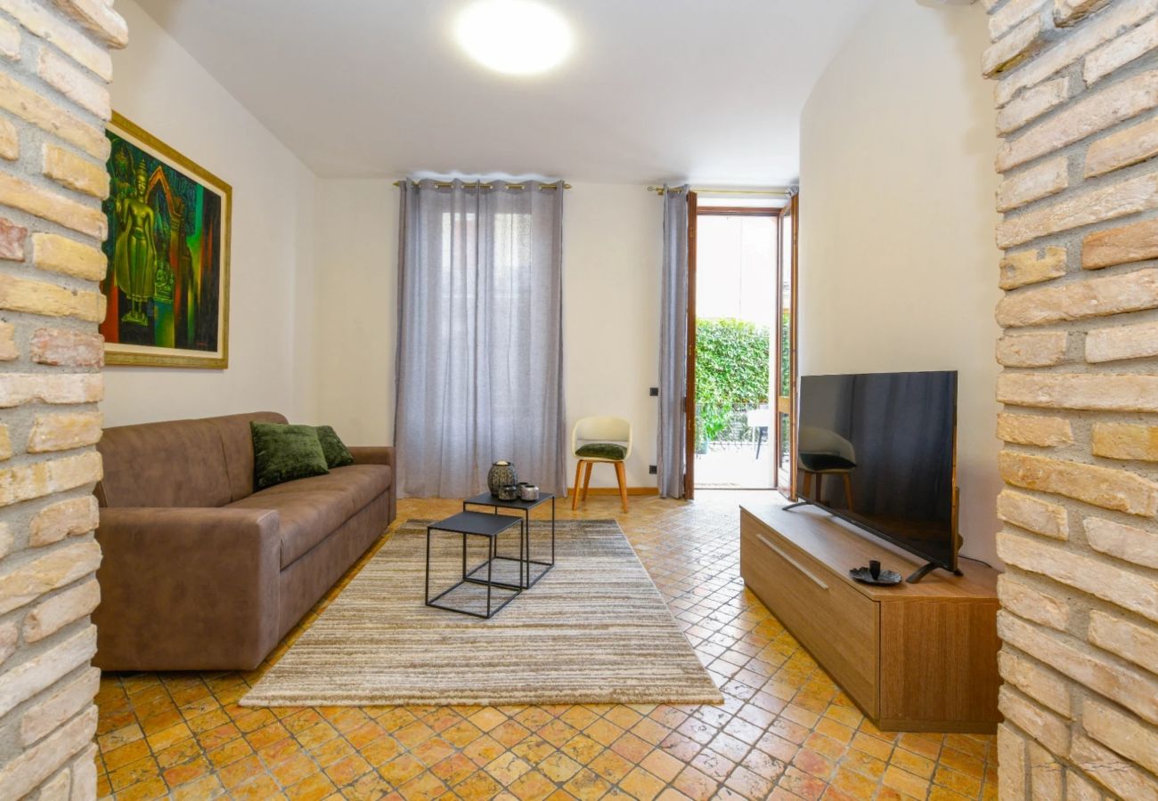 Nowoczesny salon z brązową sofą, odsłoniętymi ceglanymi łukami i TV w Desenzano