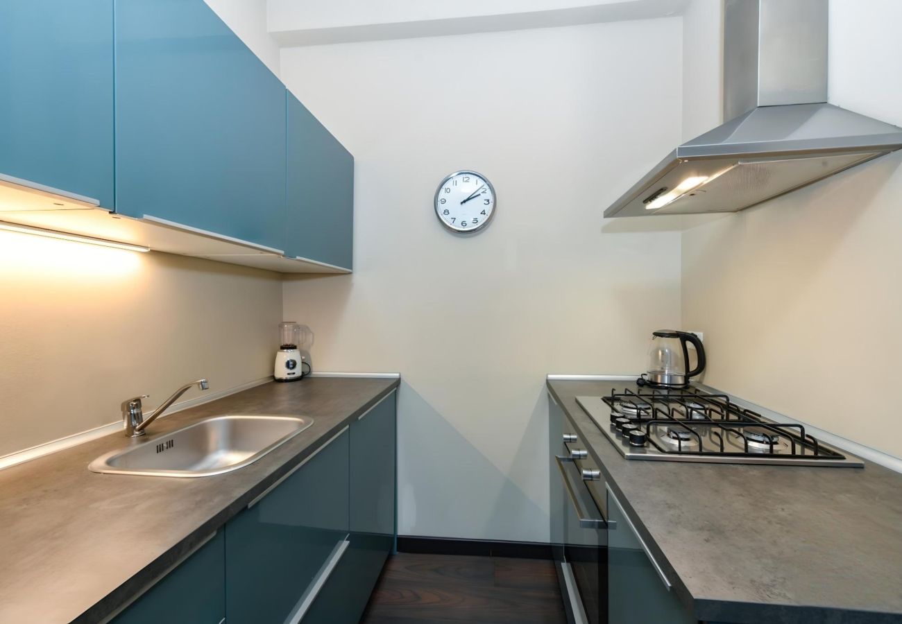 Nowoczesna kuchnia z morskimi szafkami,płytą gazową i okapem w Desenzano